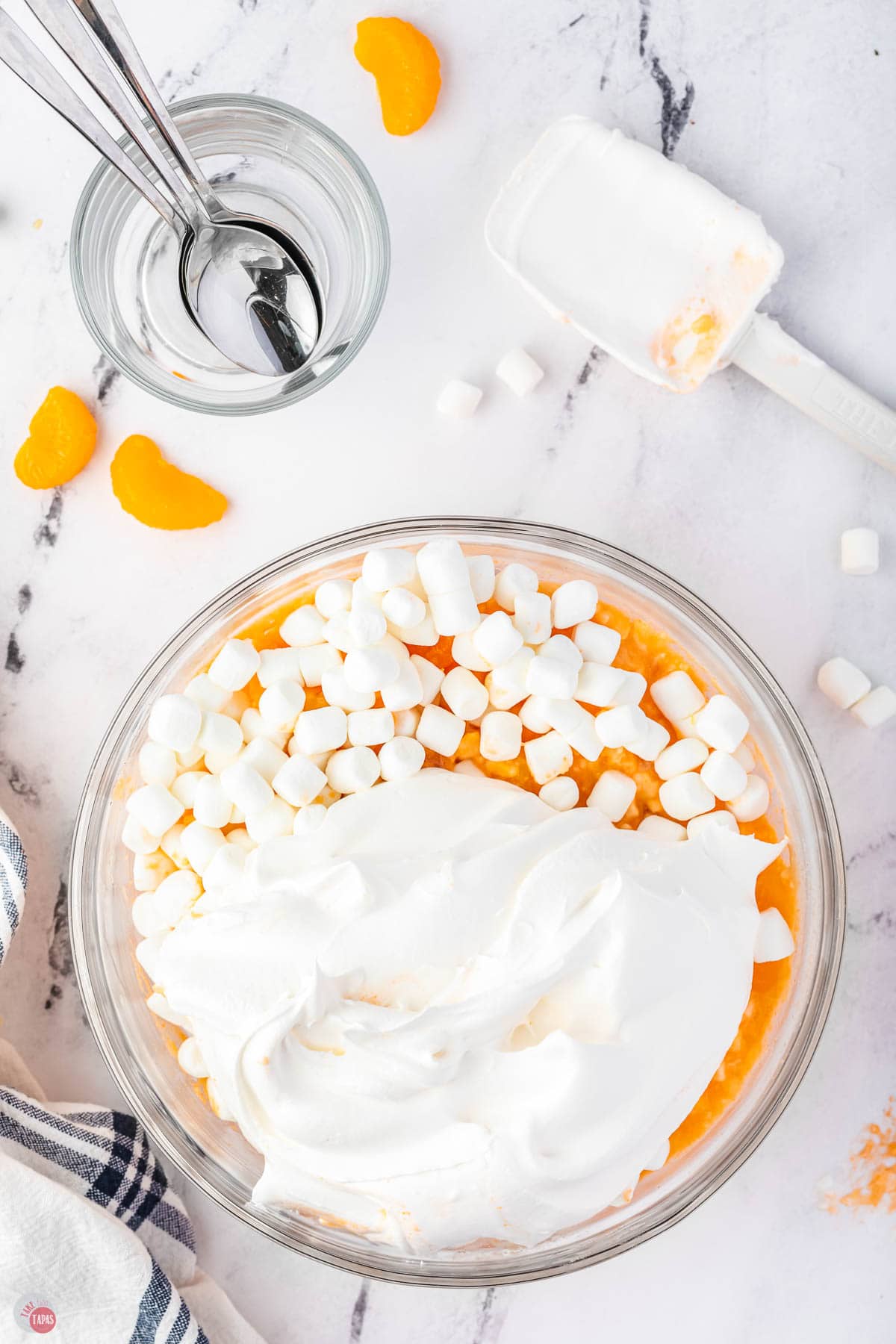 orange jello with marshmallows and cool whip on top in a bowl