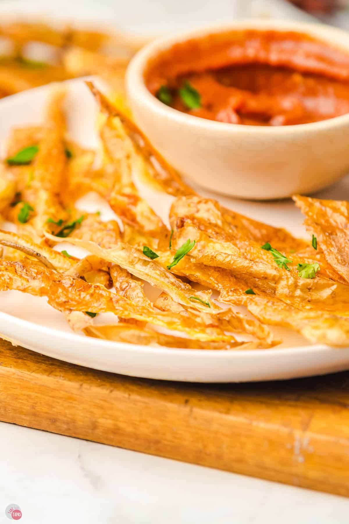 close up of potato skin chips on a white plate with a bowl of ketchup