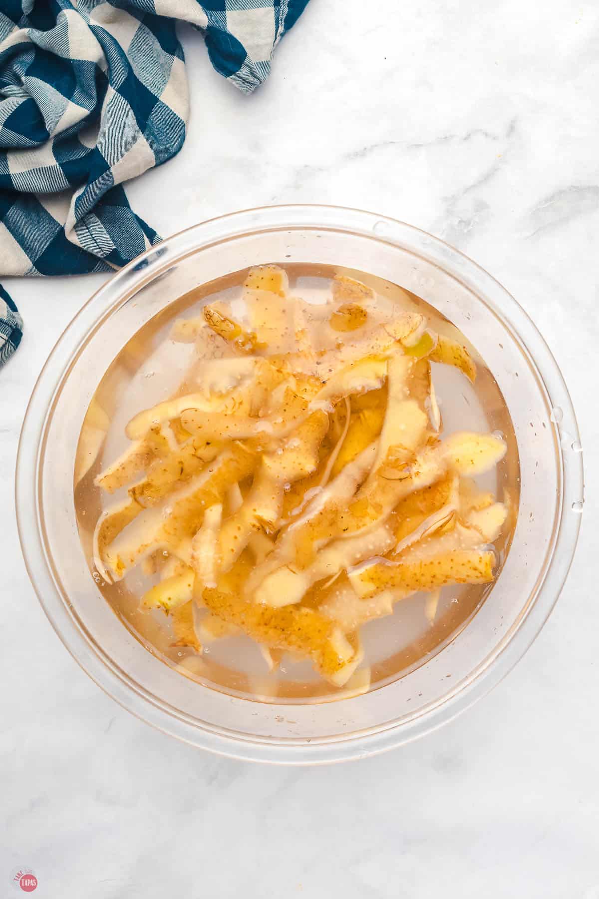 potato peels in a clear bowl filled with water