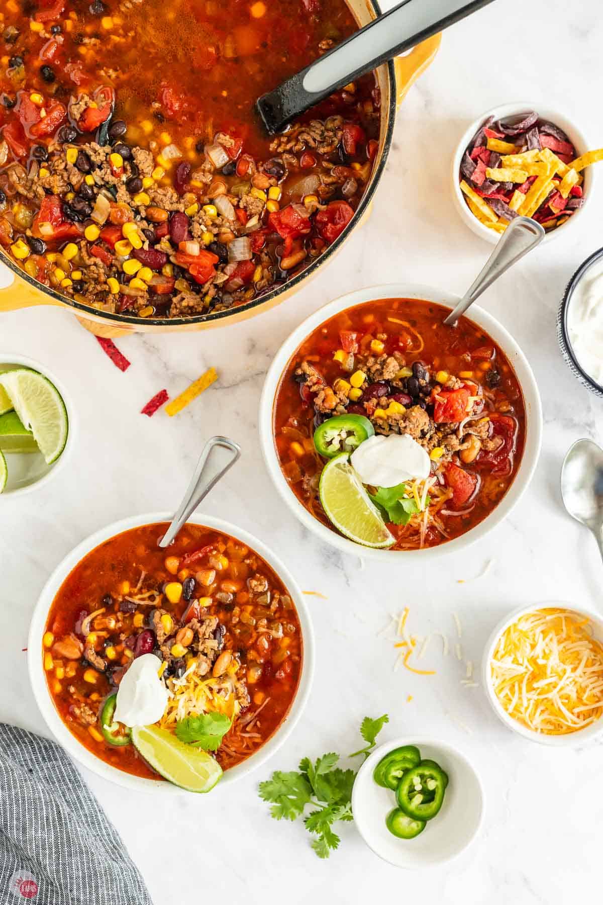 two bowls of soup with lime and avocado