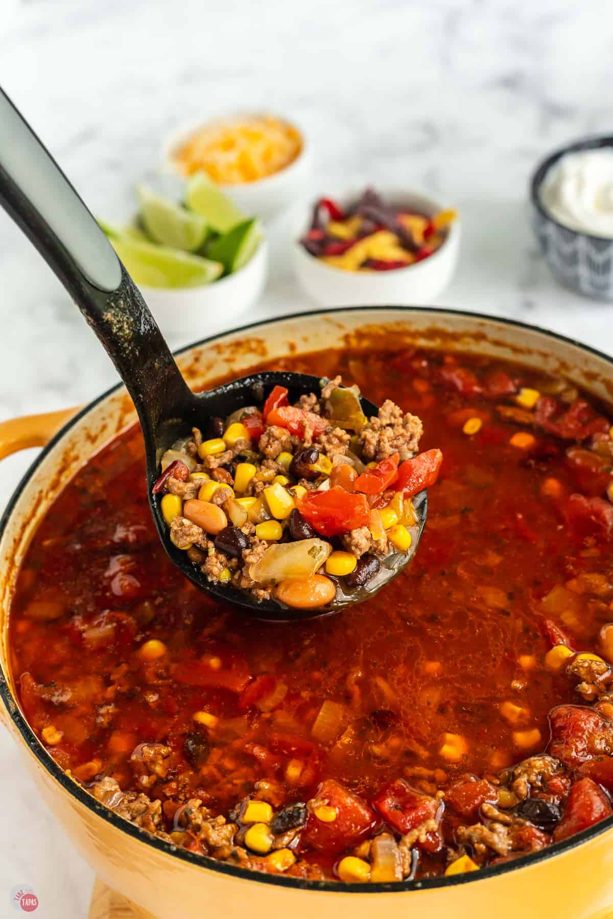 ladle of soup above a yellow pot