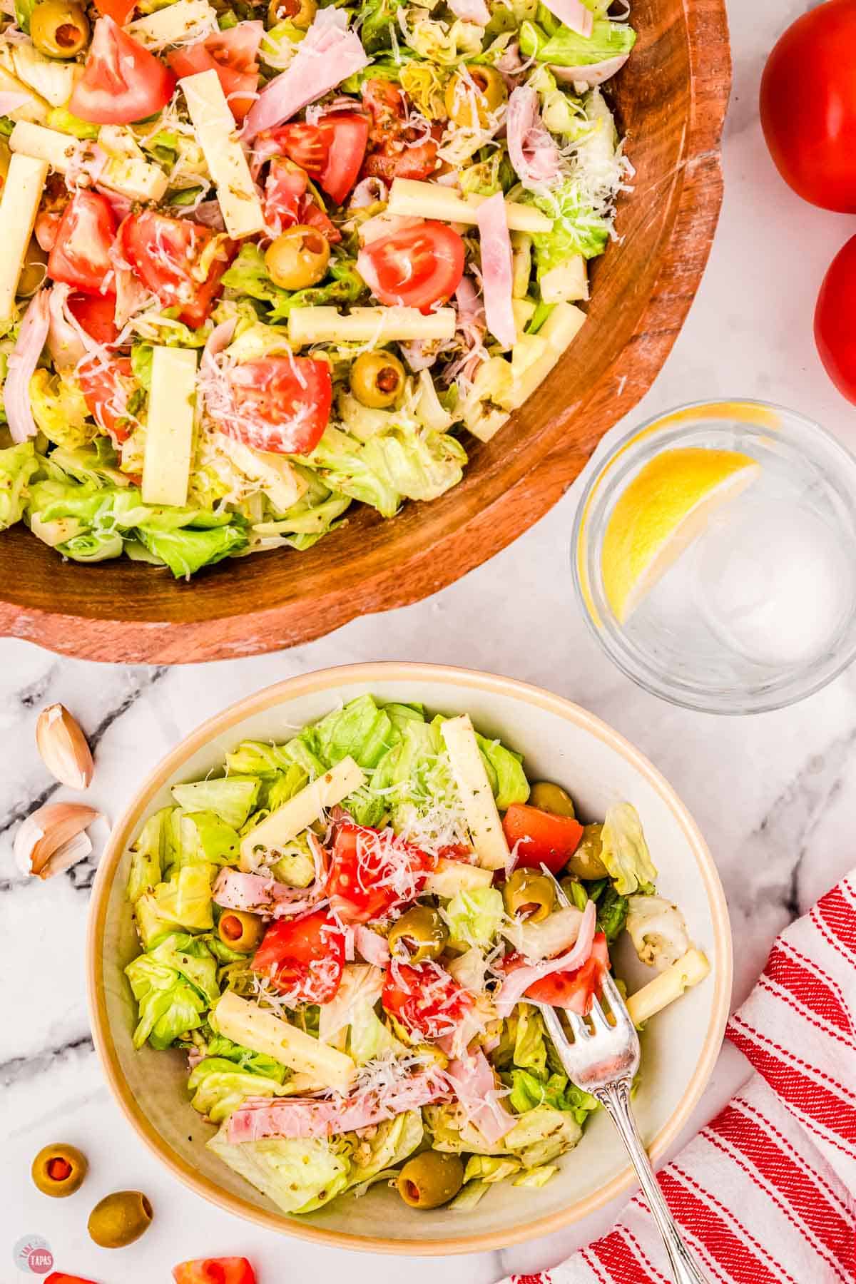 A bowl of salad with tomatoes, olives and cheese.