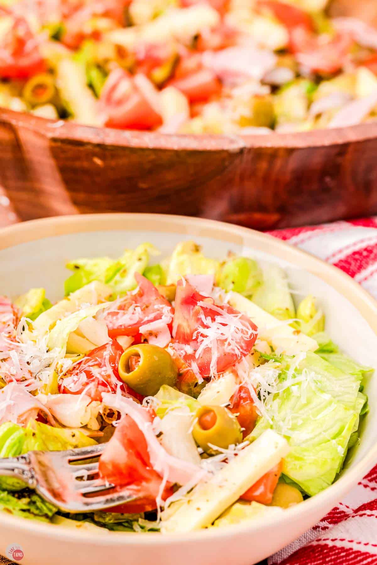 A salad with meat and cheese on top of it.