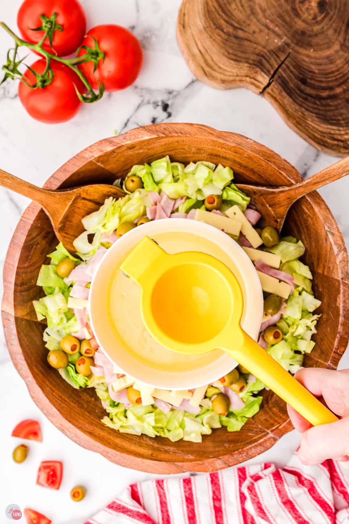 Salad in a bowl with a yellow spoon.
