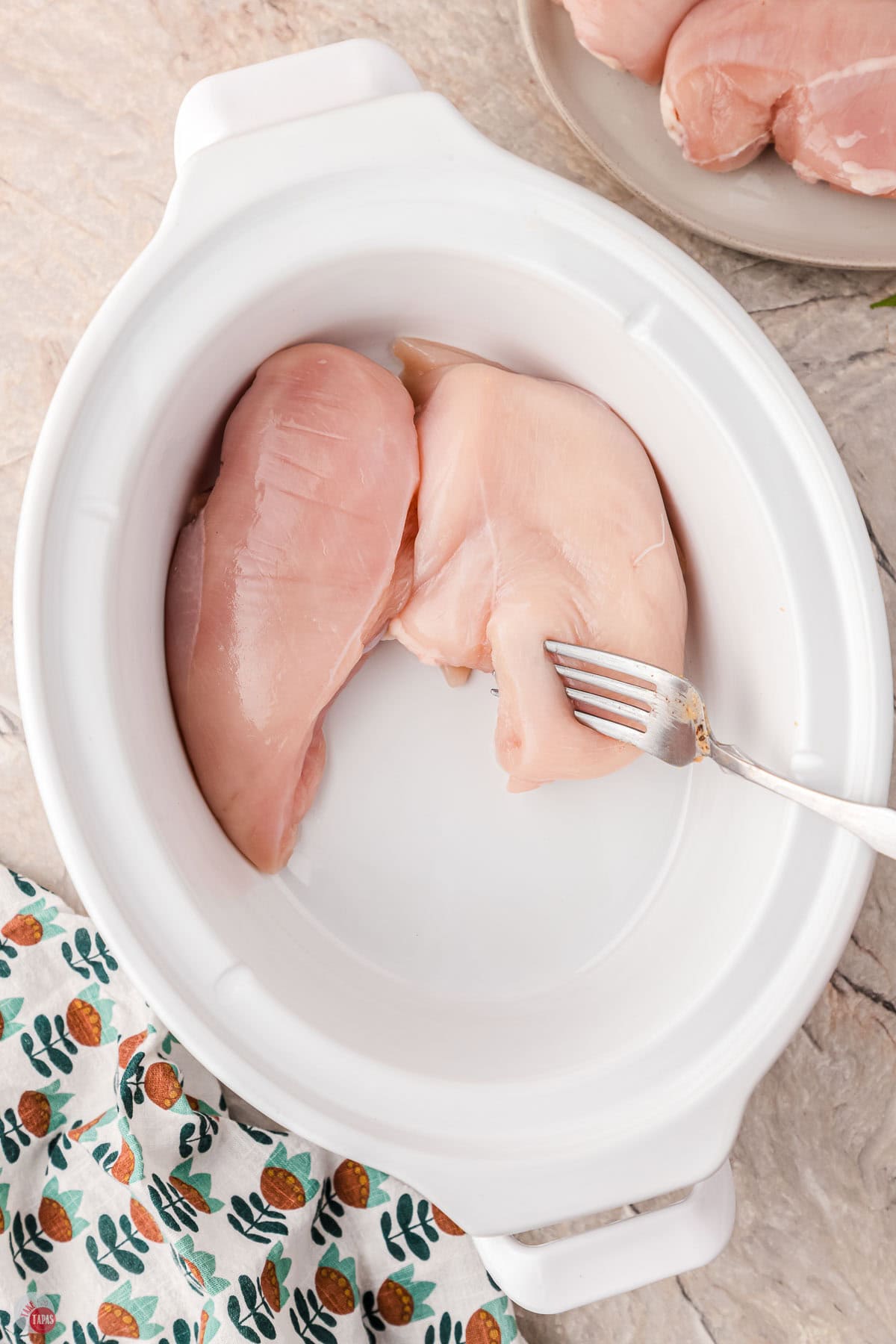 two pieces of chicken in a white crock pot