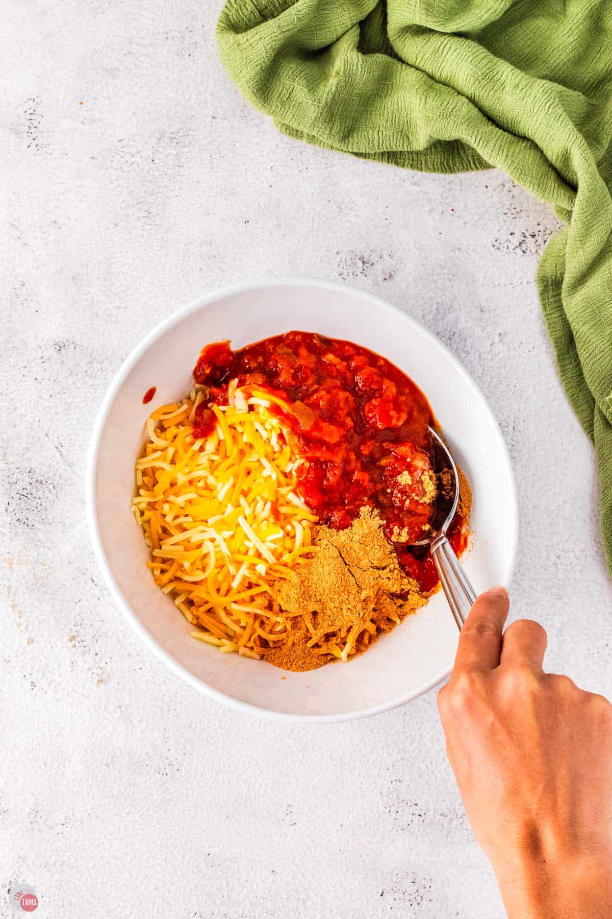 spices mixed with shredded cheese in a white bowl with a fork