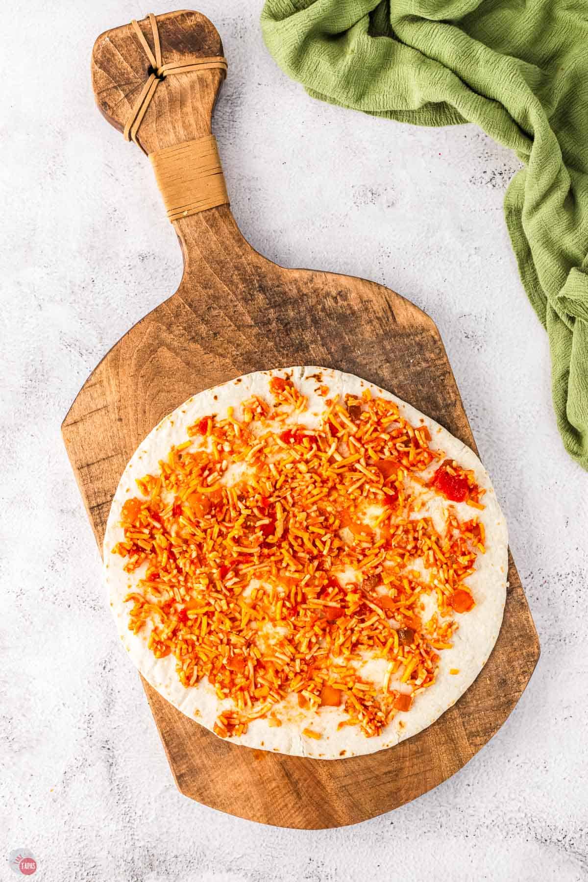 flour tortilla on a board with chicken and spices on it