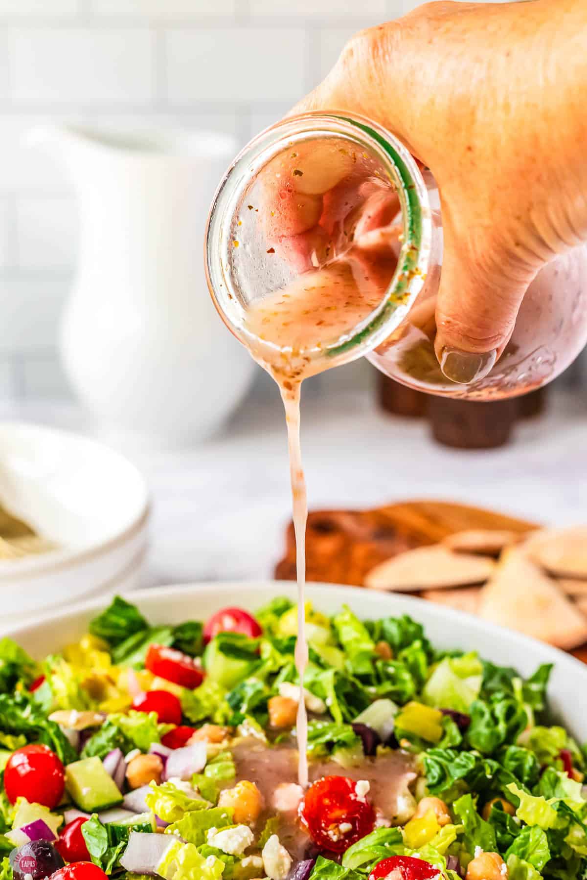 dressing being poured onto a salad