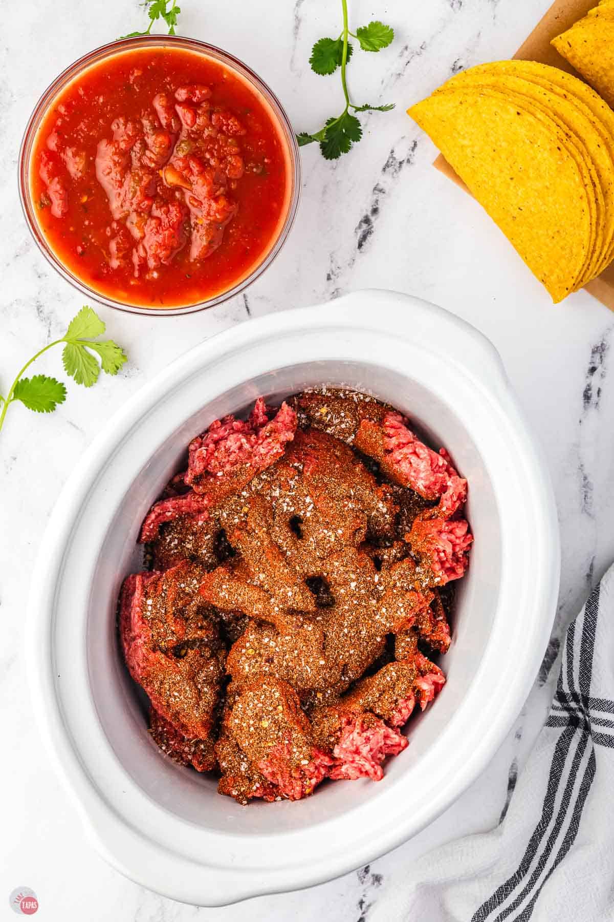 ground beef covered in seasoning in a white bowl