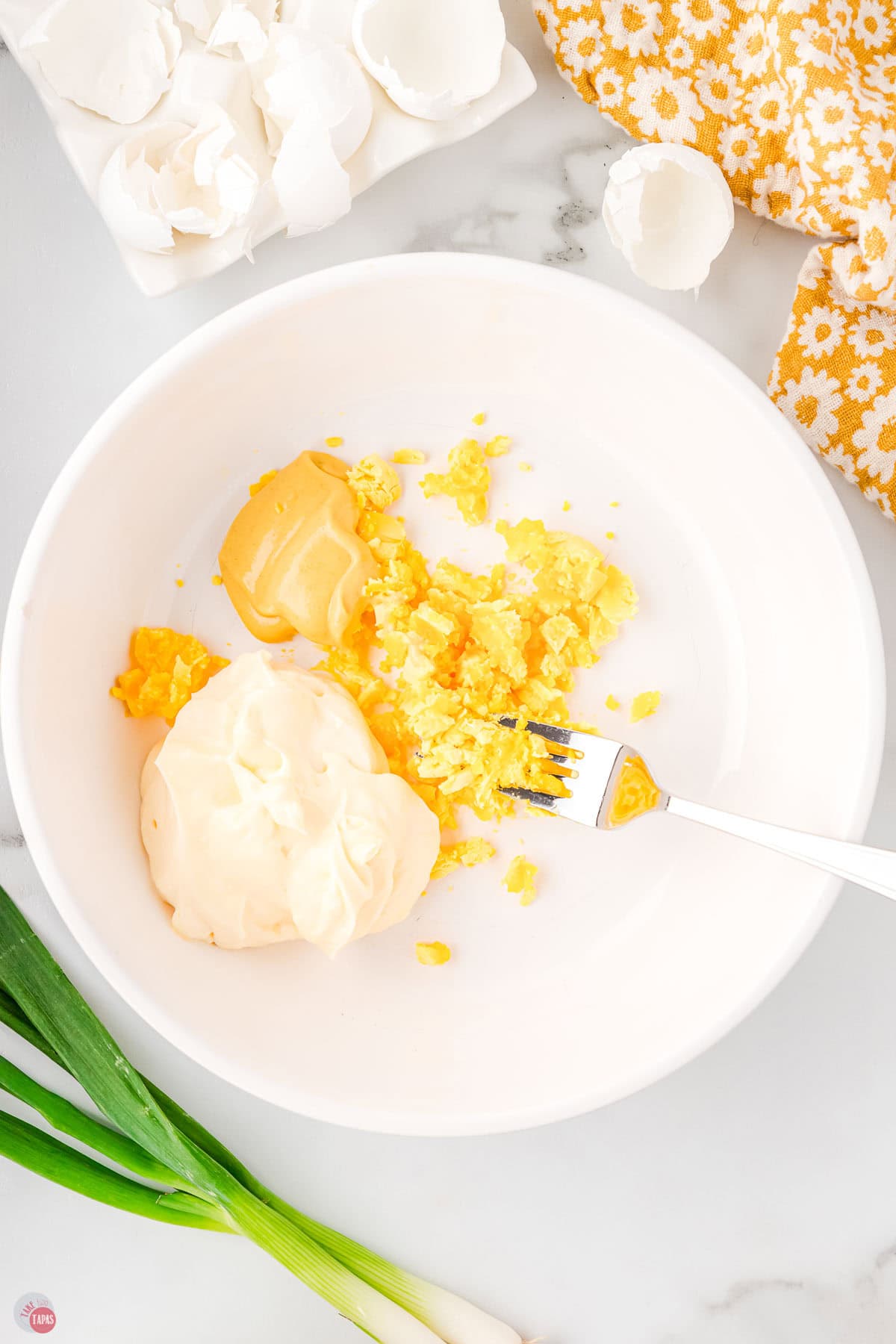 egg yolks and mayo in a white bowl with a fork
