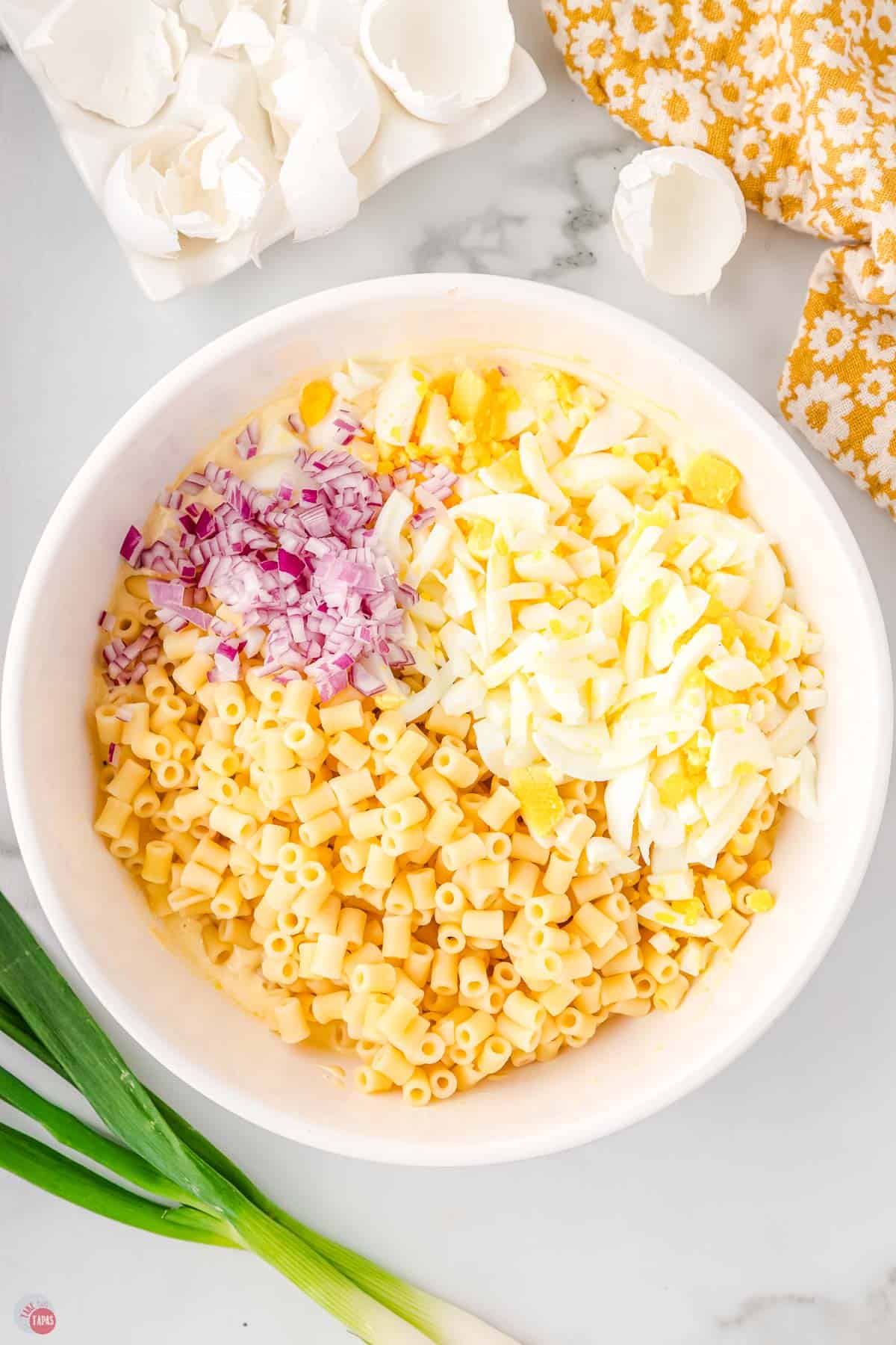 cooked pasta, diced egg, and red onion in a white bowl