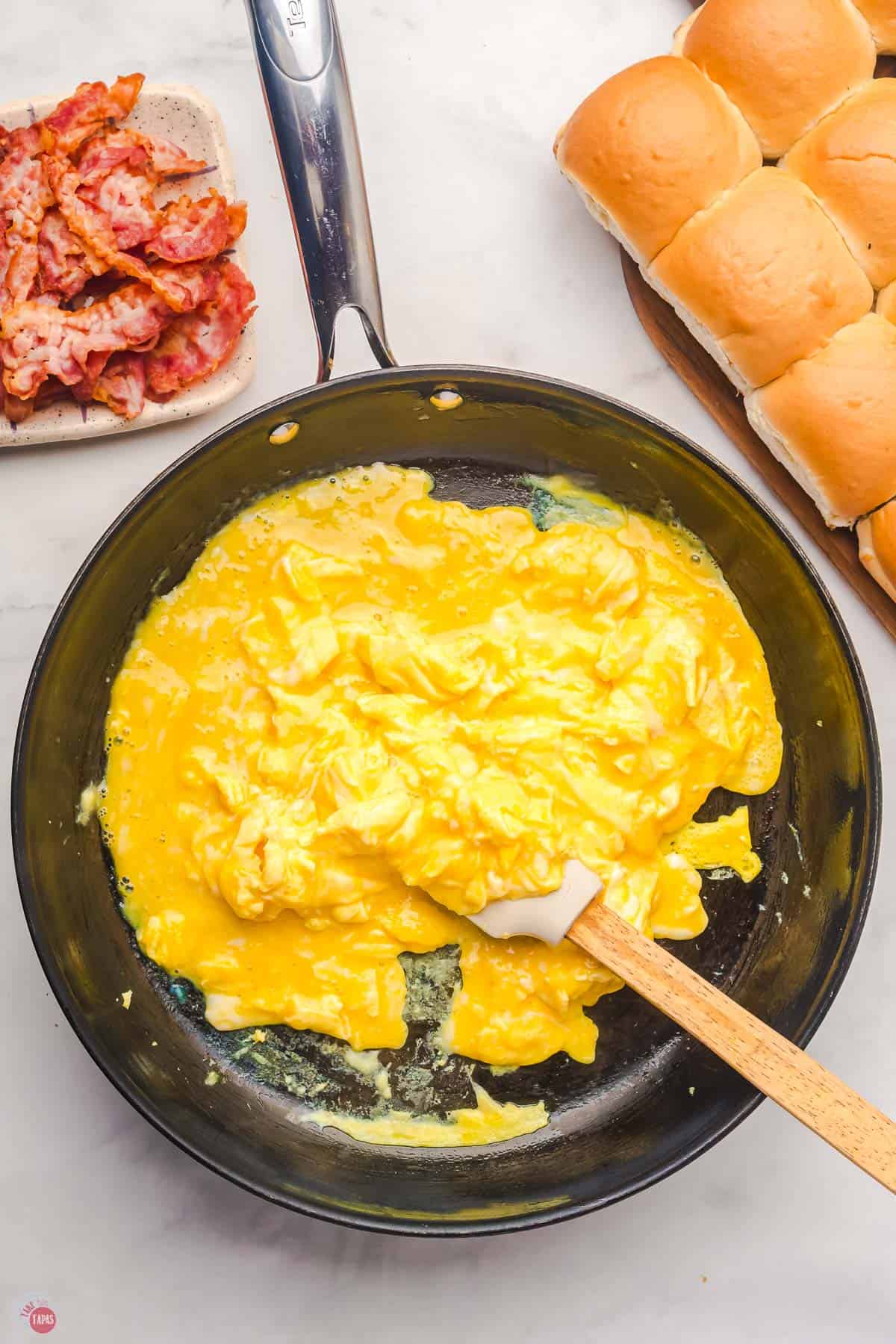 scrambled eggs cooking in a pan with a spatula