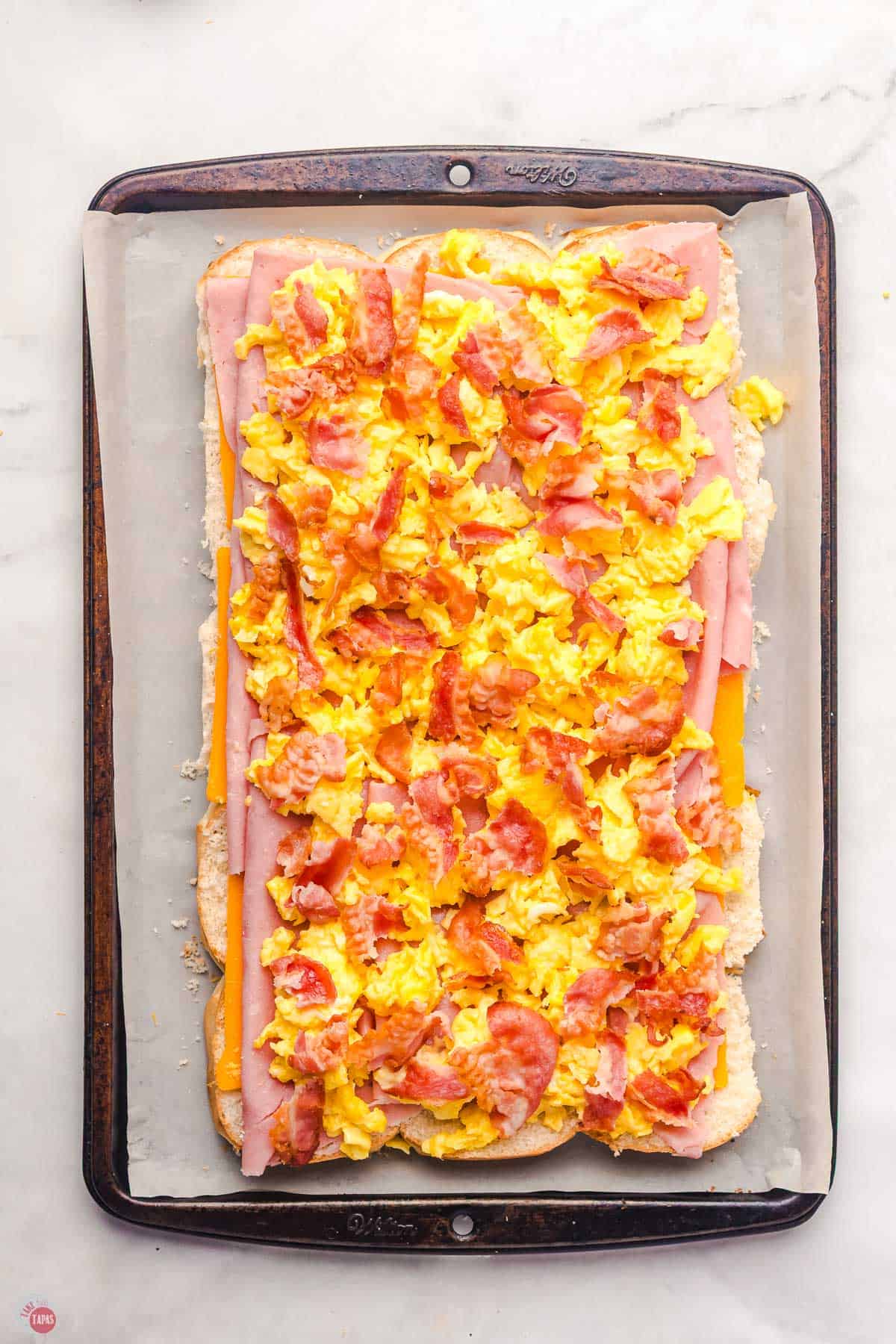 open face breakfast sliders on a baking sheet before they are cooked