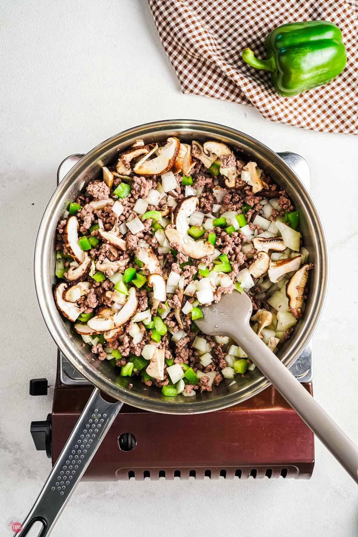 skillet with onions, peppers, and mushrooms in a skillet