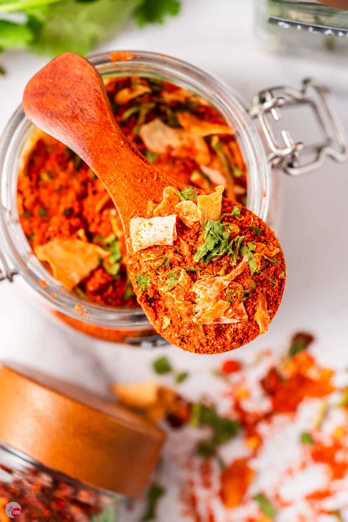 jar of red spices with a spoon balancing on top