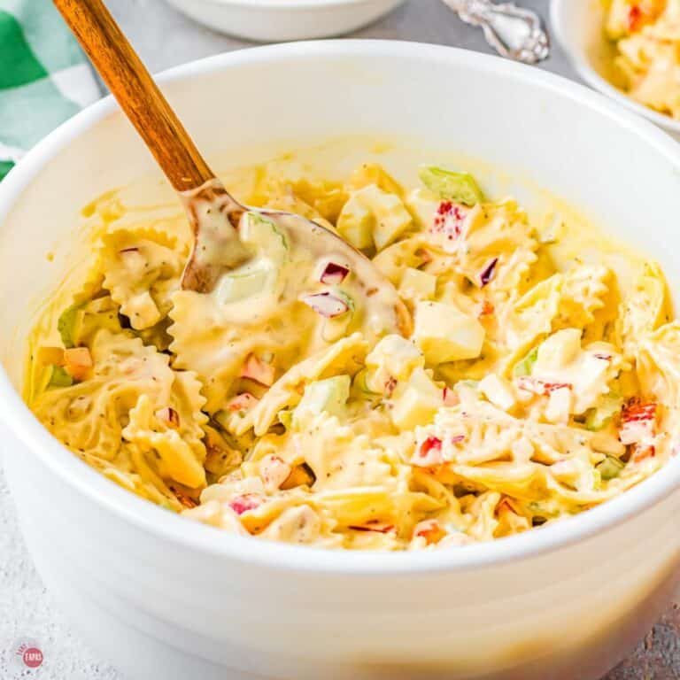 amish pasta salad in a white bowl with wood spoon