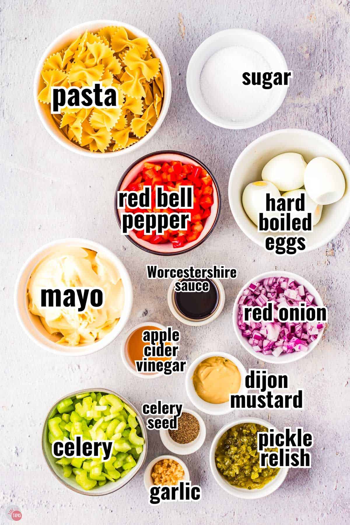 ingredients for pasta salad recipe in individual bowls with text overlay labeling them