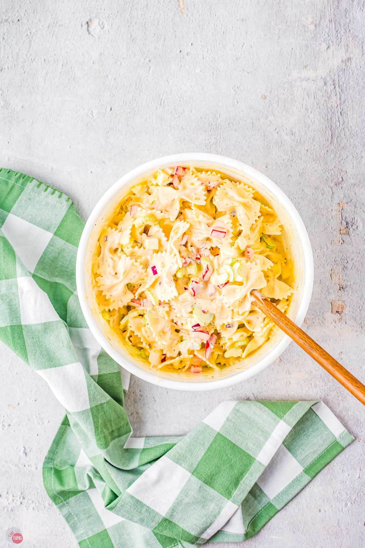 amish pasta salad in a white bowl with wood spoon