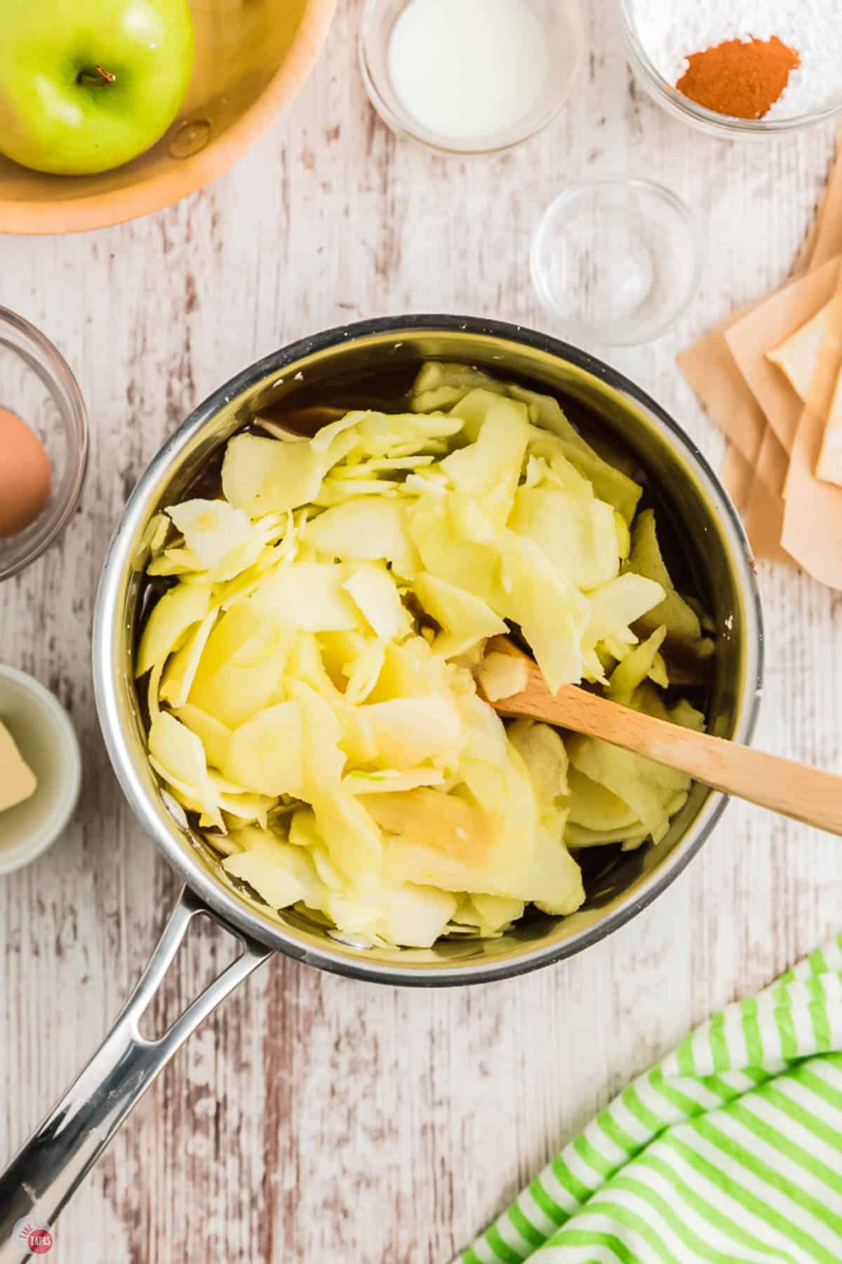 saucepan full of sliced apples with a wood spoon
