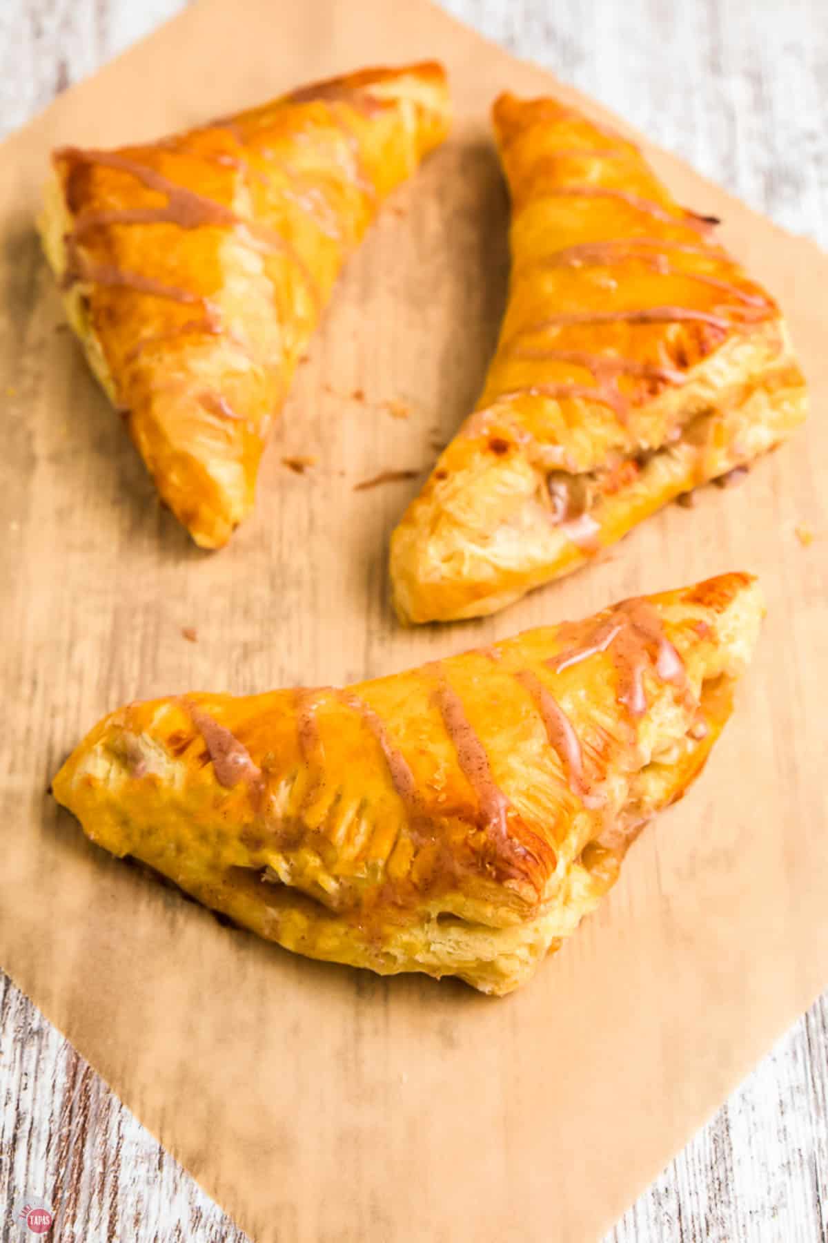 three apple turnovers on parchment paper