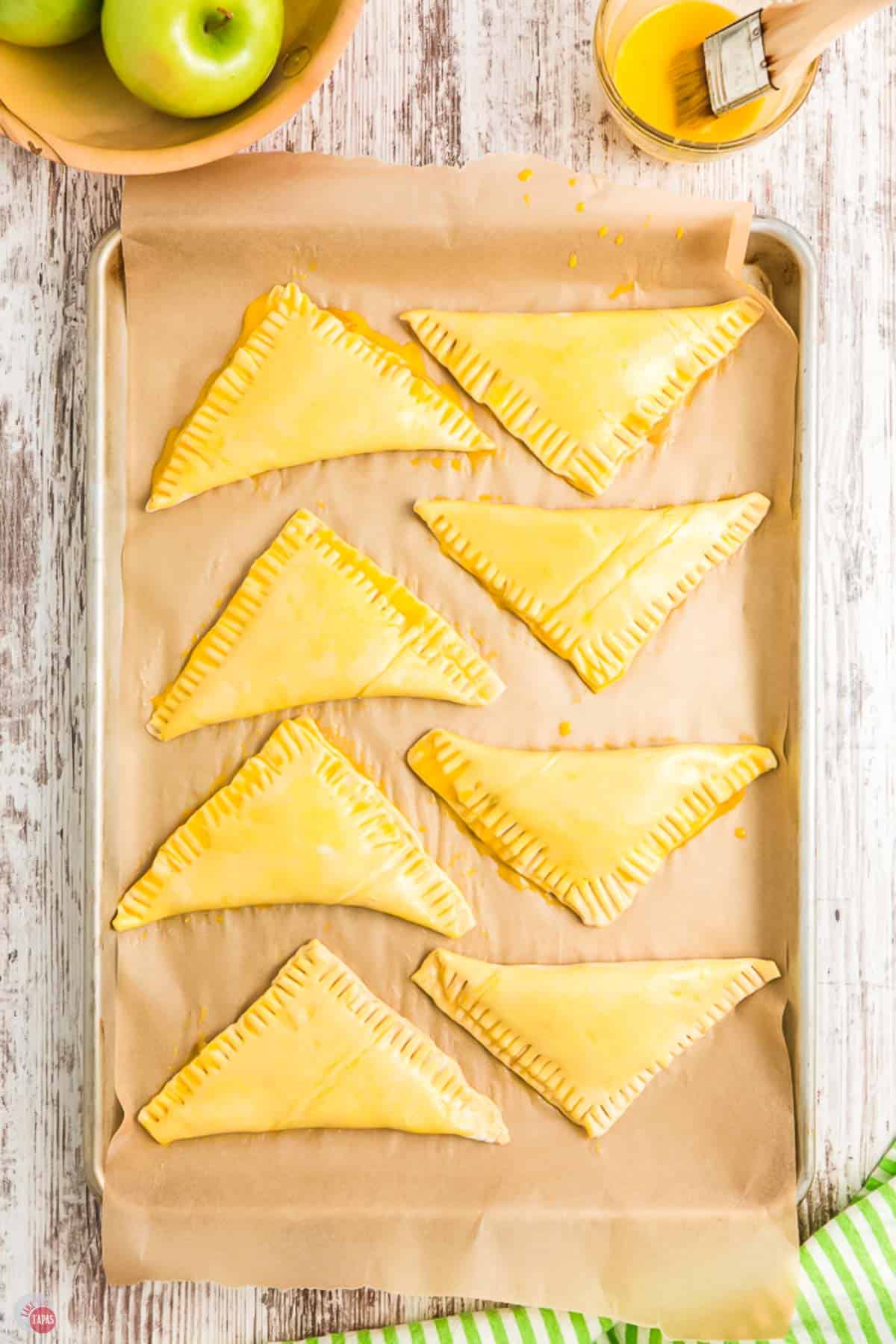 unbaked apple turnovers on a baking sheet with parchment paper