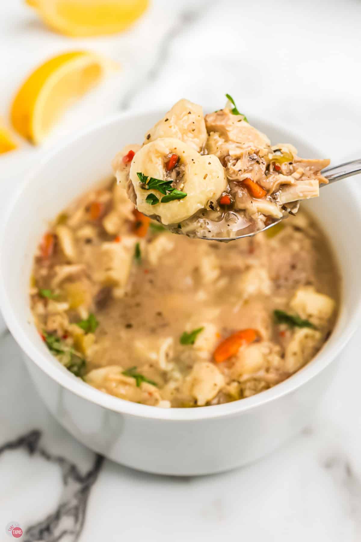 spoon with soup in it hovering over a bowl
