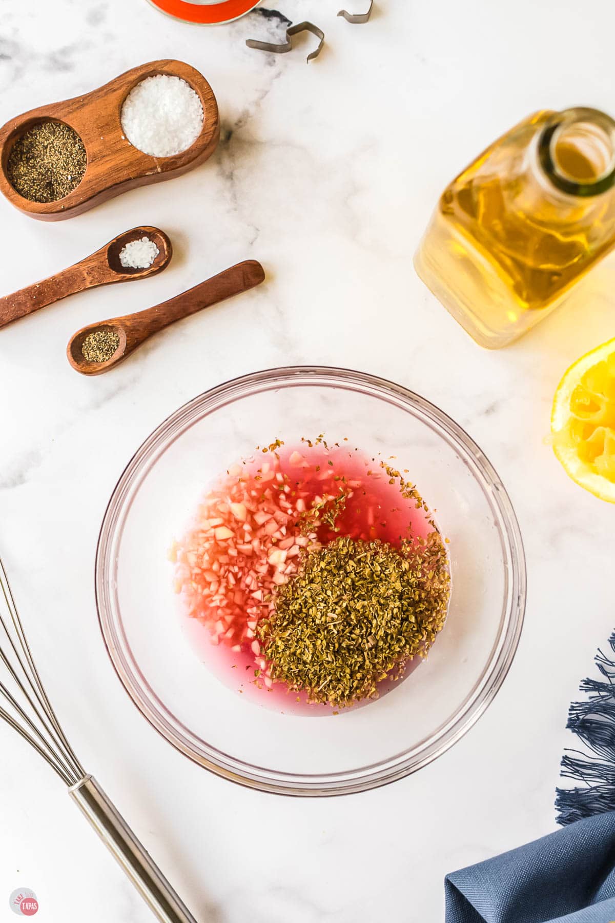 vinegar and spices in a clear bowl with a whisk next to it