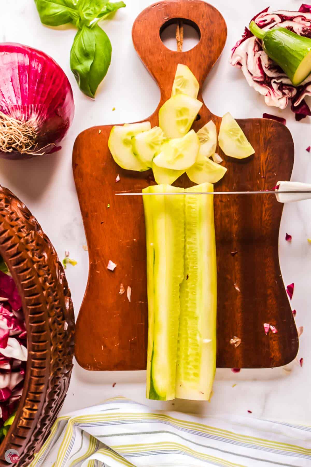 knife slicing a cucumber for a salad on a cutting board