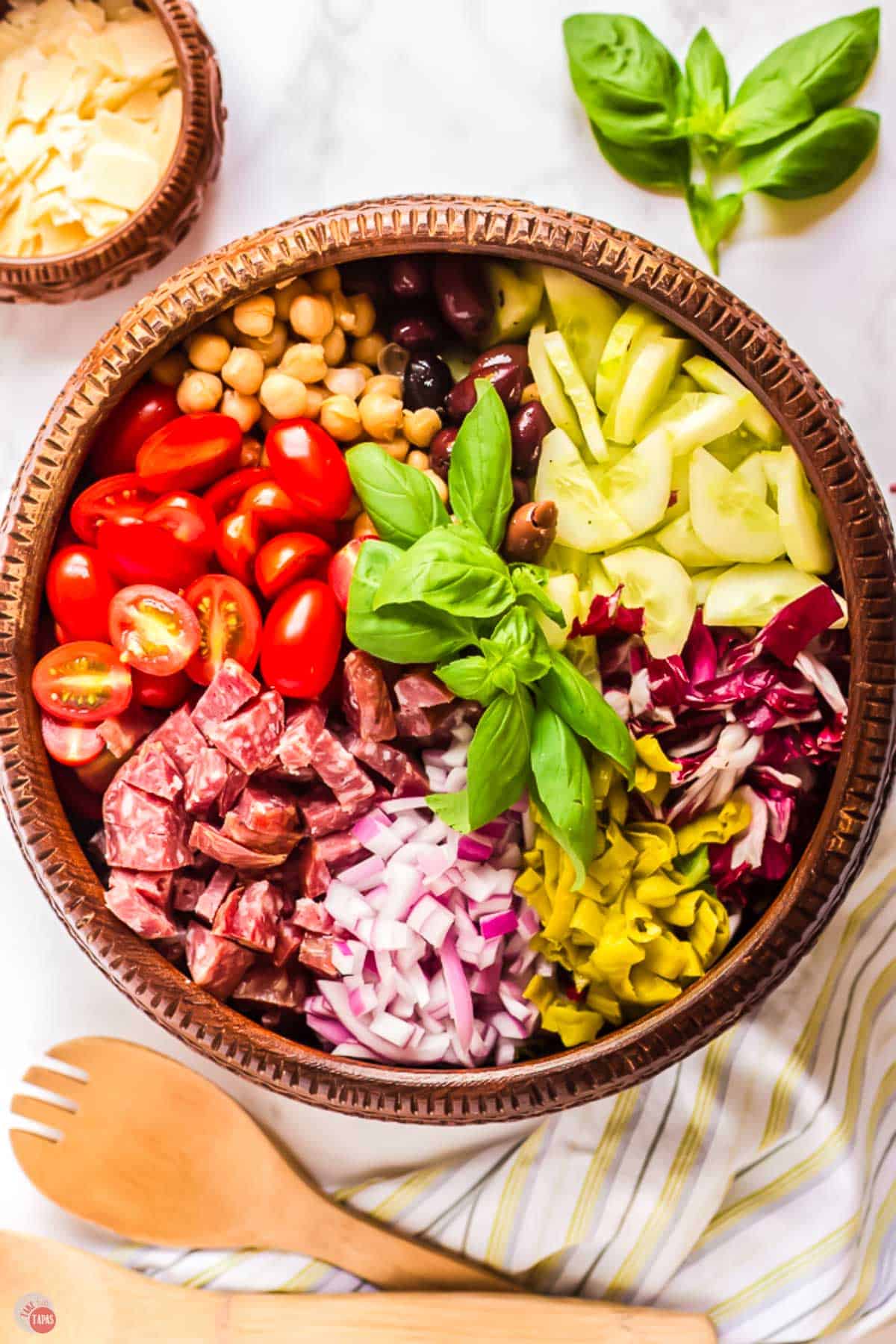 ingredients for a chopped salad in a brown salad bowl before it's mixed up