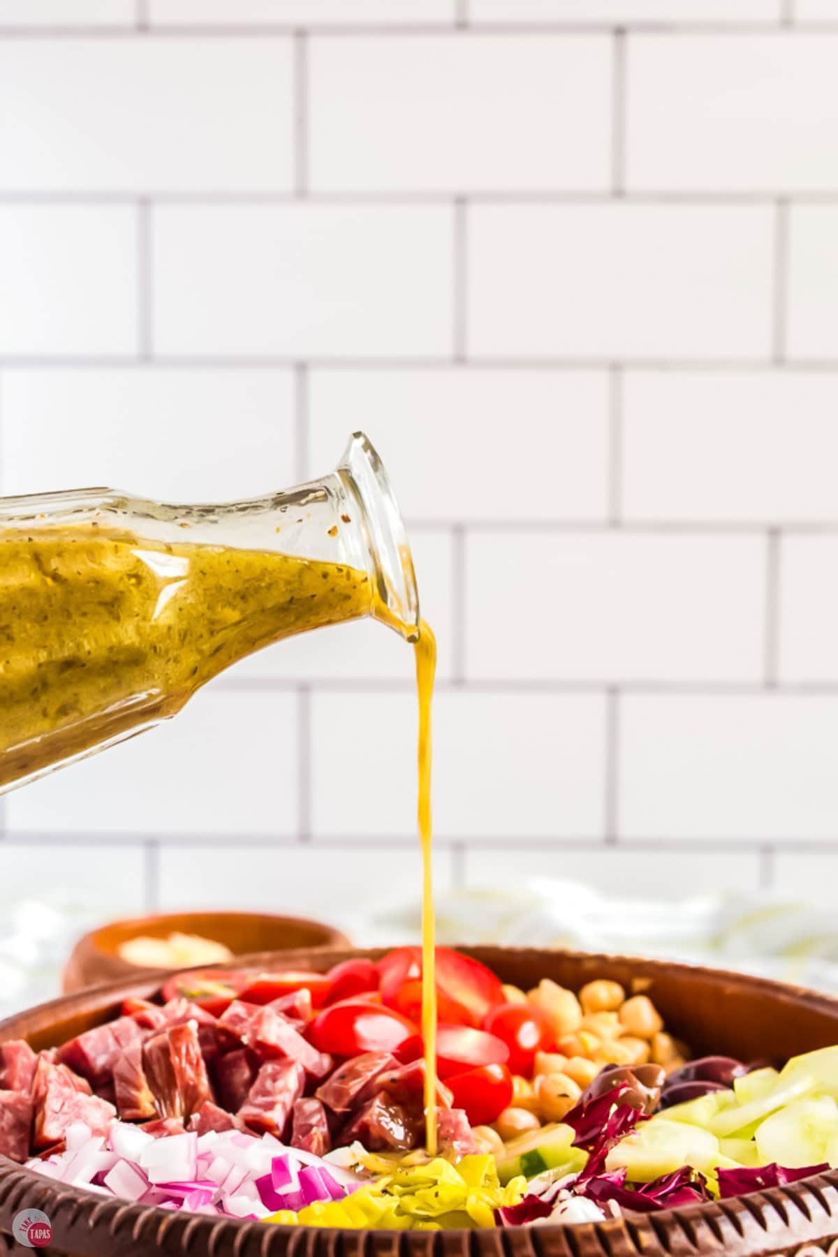 jar of salad dressing pouring dressing onto a salad