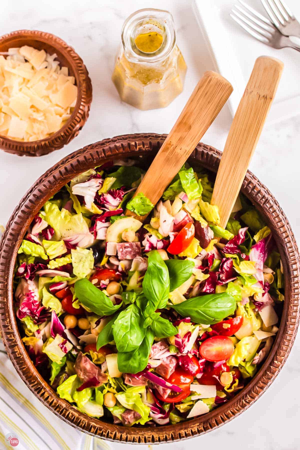 bowl of chopped italian salad in a wood bowl with two spoons