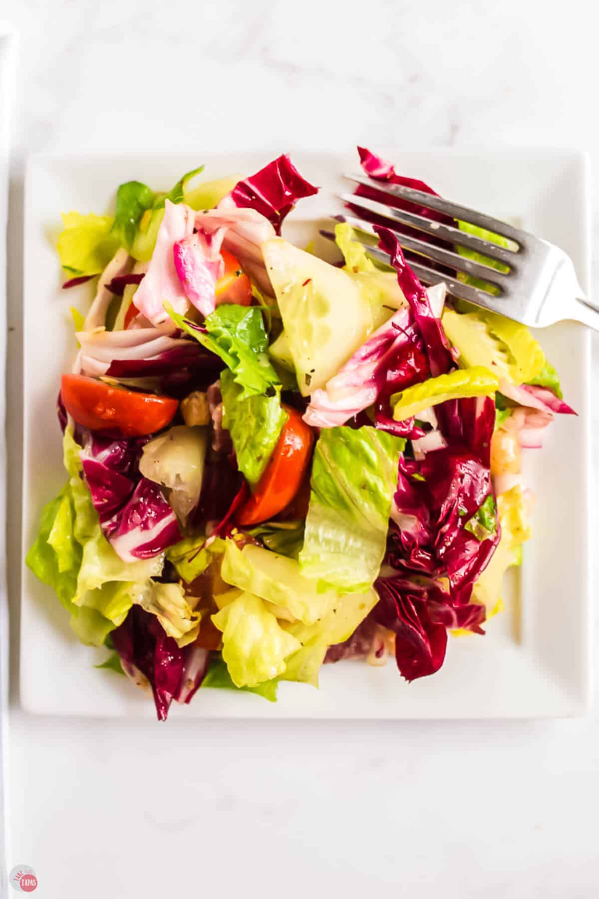 small white plate of salad with a fork