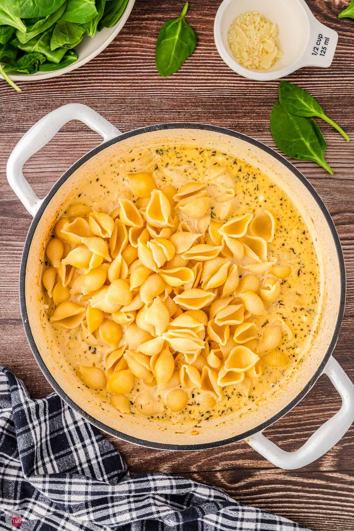 creamy soup in yellow pot with cooked pasta shells in it