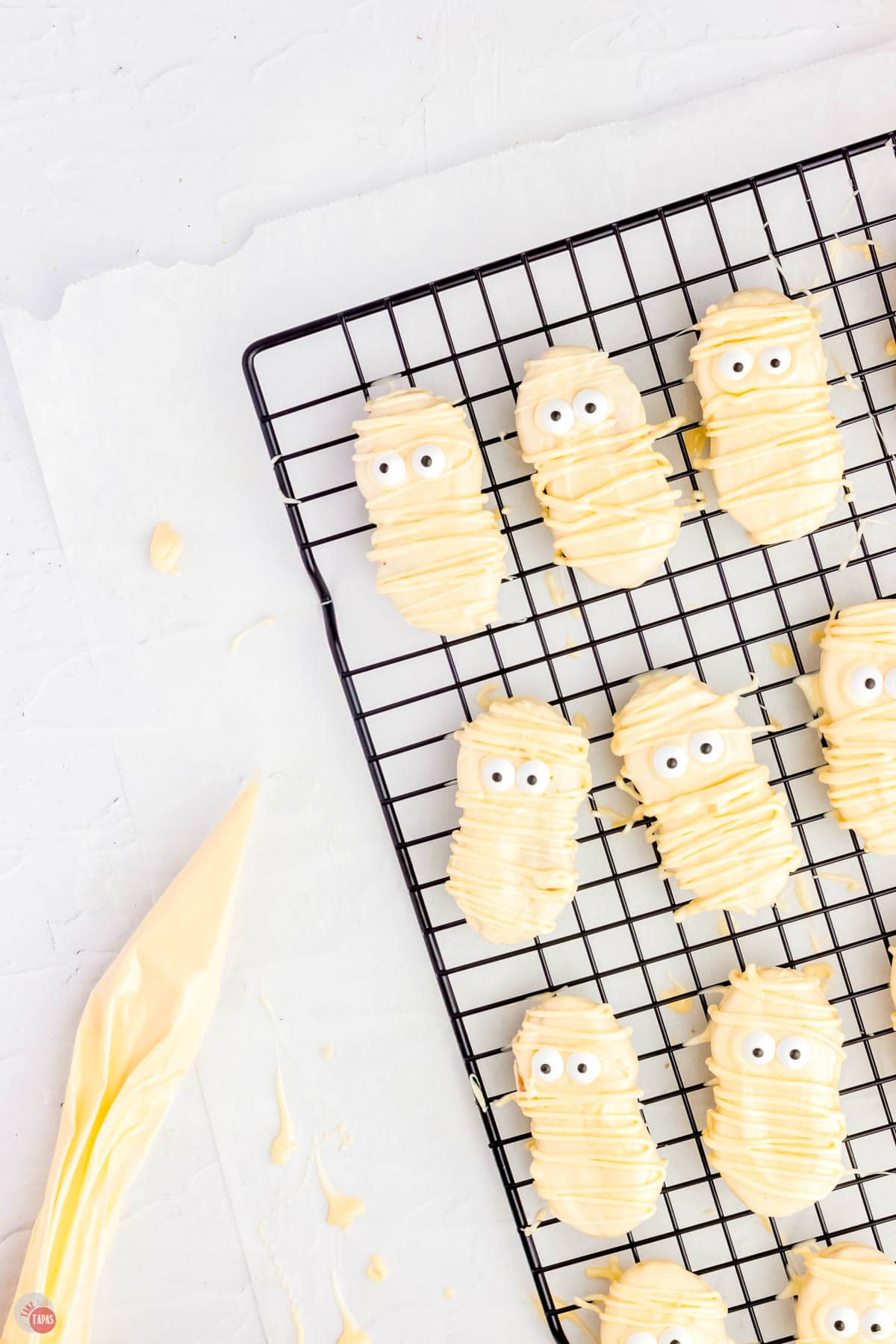 cookies on a rack with a piping bag full of white chocolate next to it