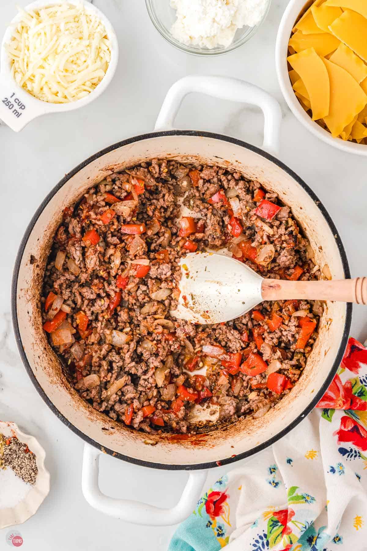 pot with cooked ground beef and bell peppers being stirred with a white spatula