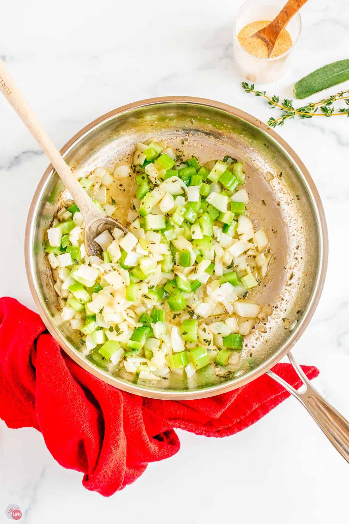 skillet with wood spoon stirring celery and onions while they're cooking