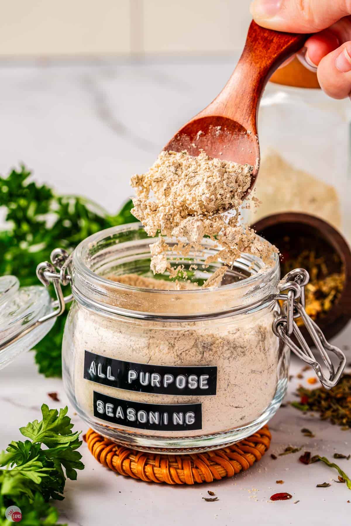 jar of all purpose seasoning with a spoon sprinkling some out
