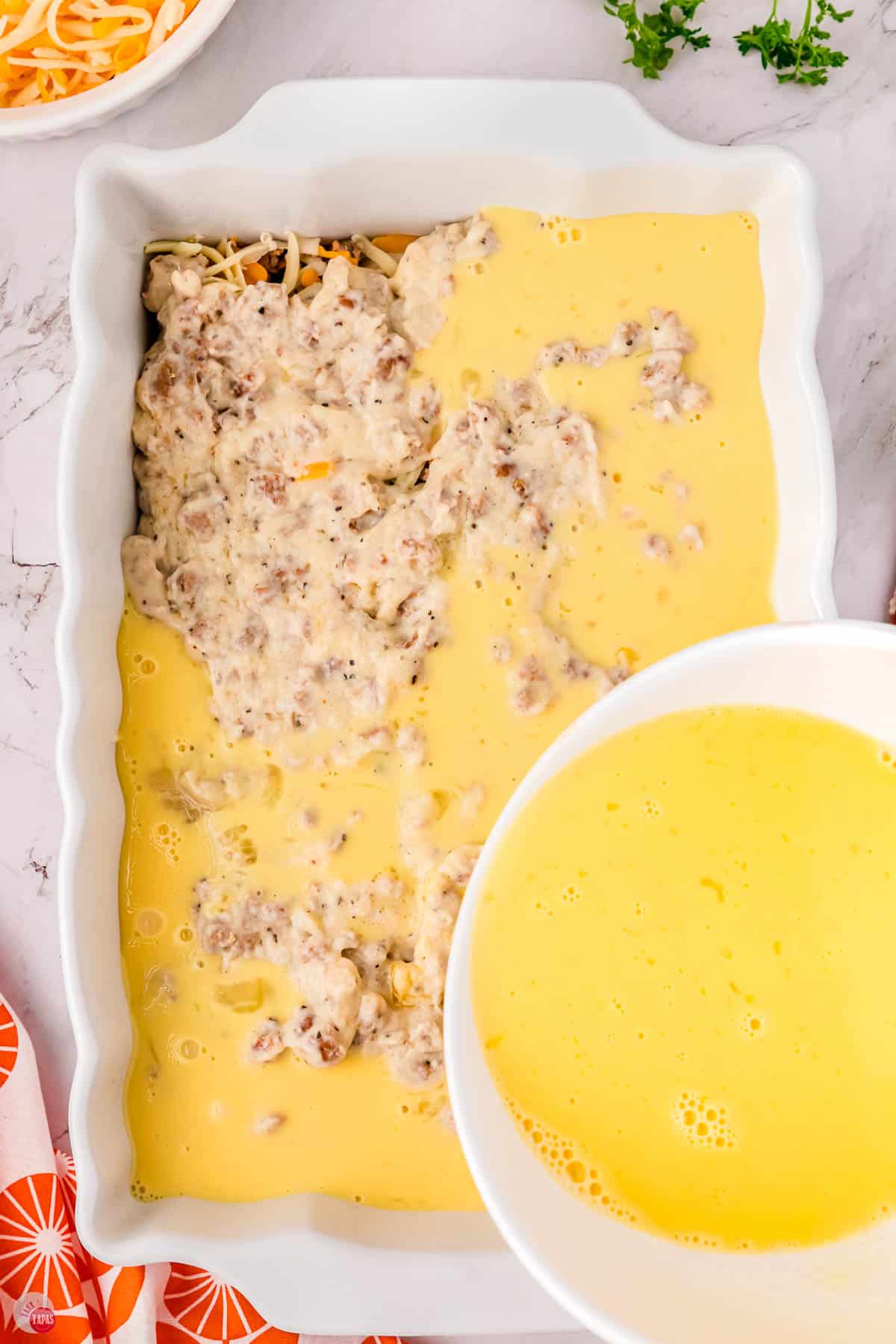 whisked egg being poured on top of a casserole