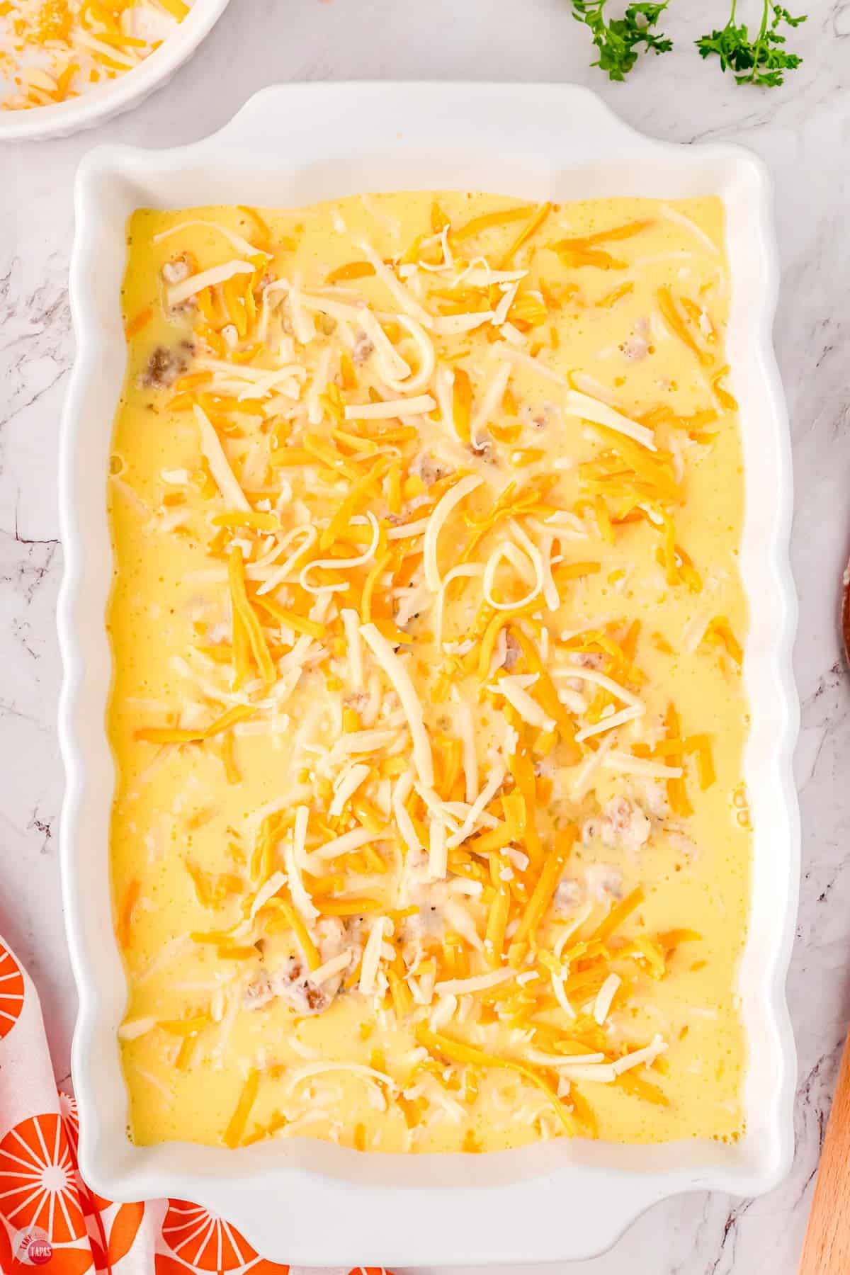 unbaked egg casserole topped with shredded cheese