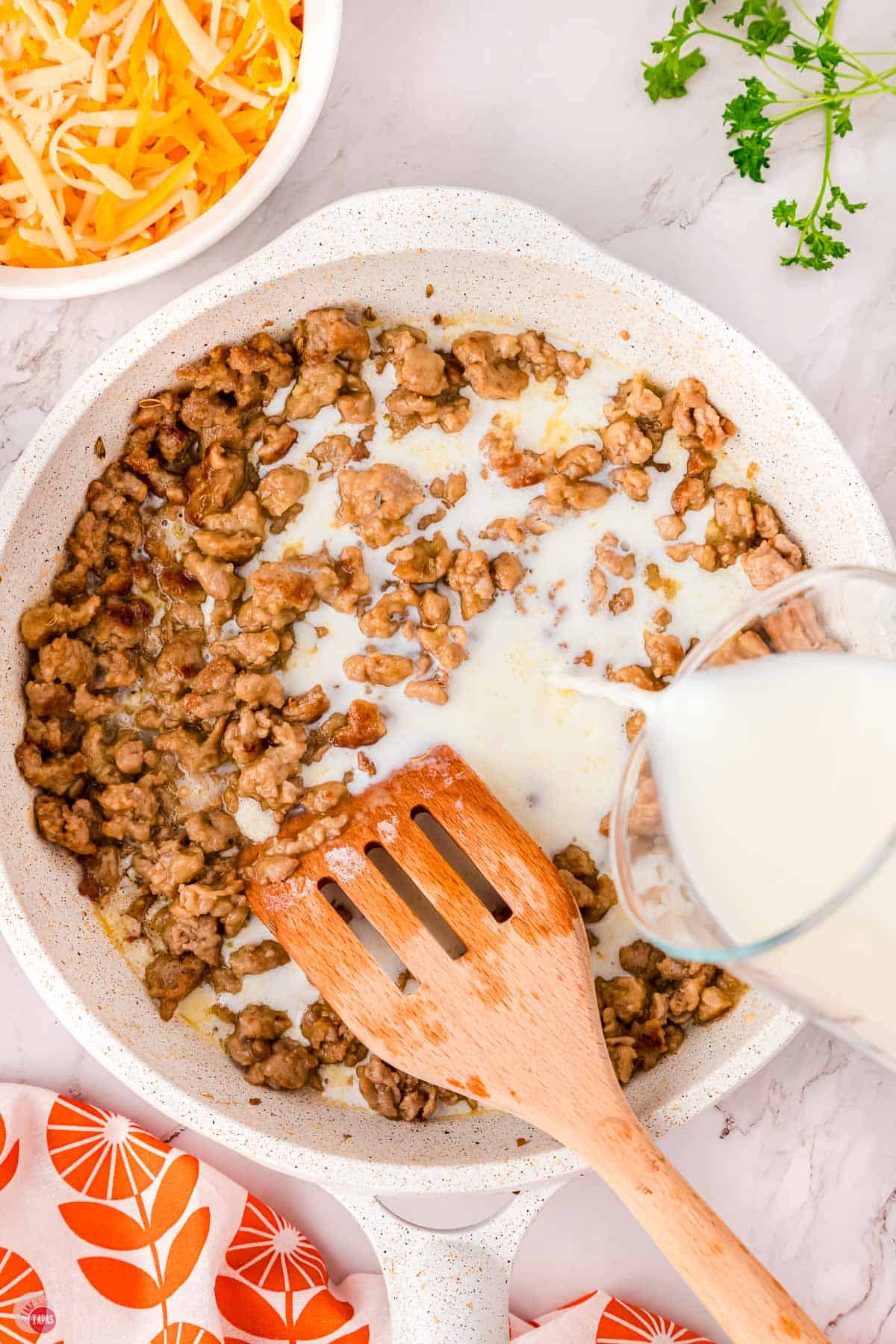 hand pouring into a skillet of cooked pork sausage