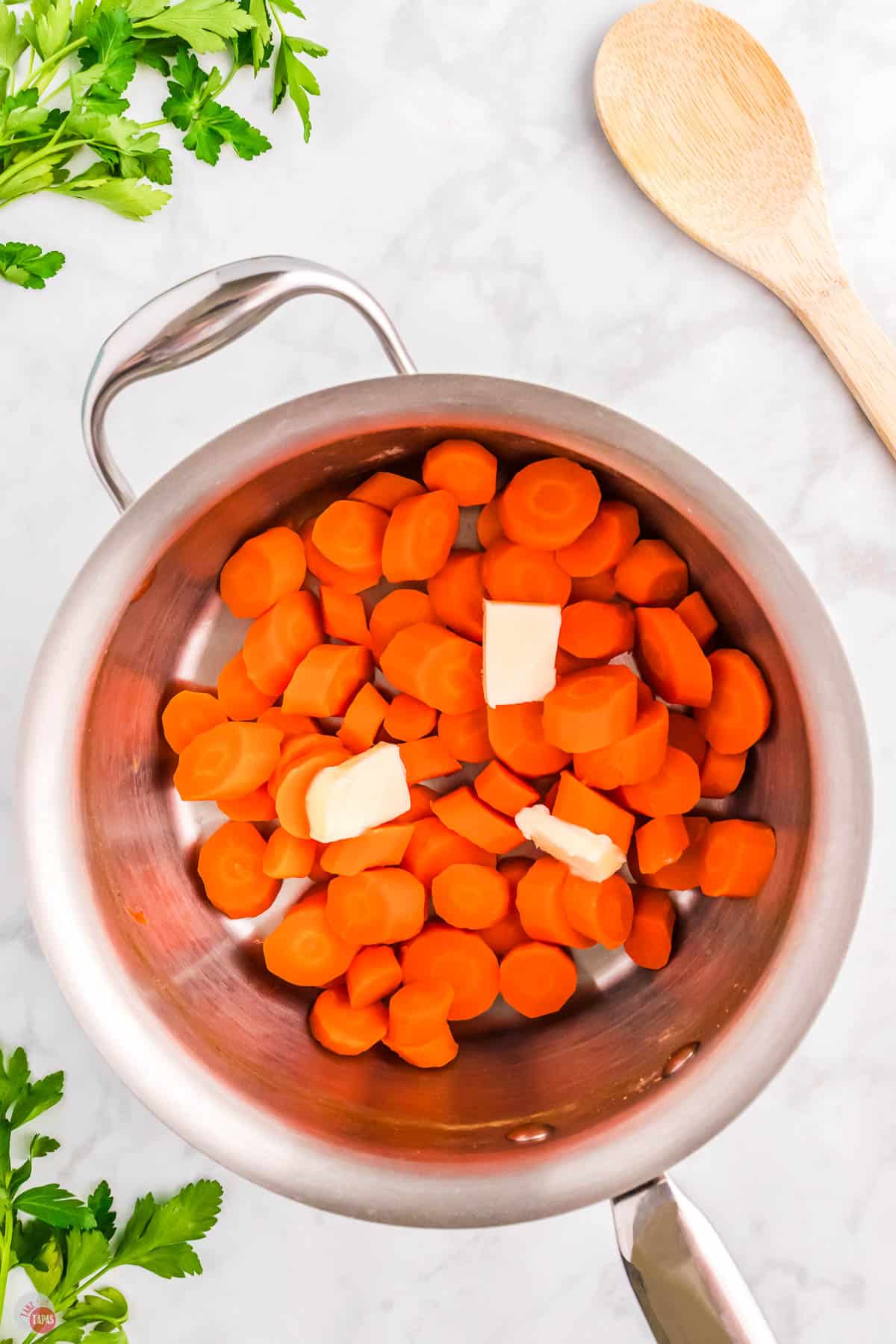 sliced carrots in a pot with pats of butter