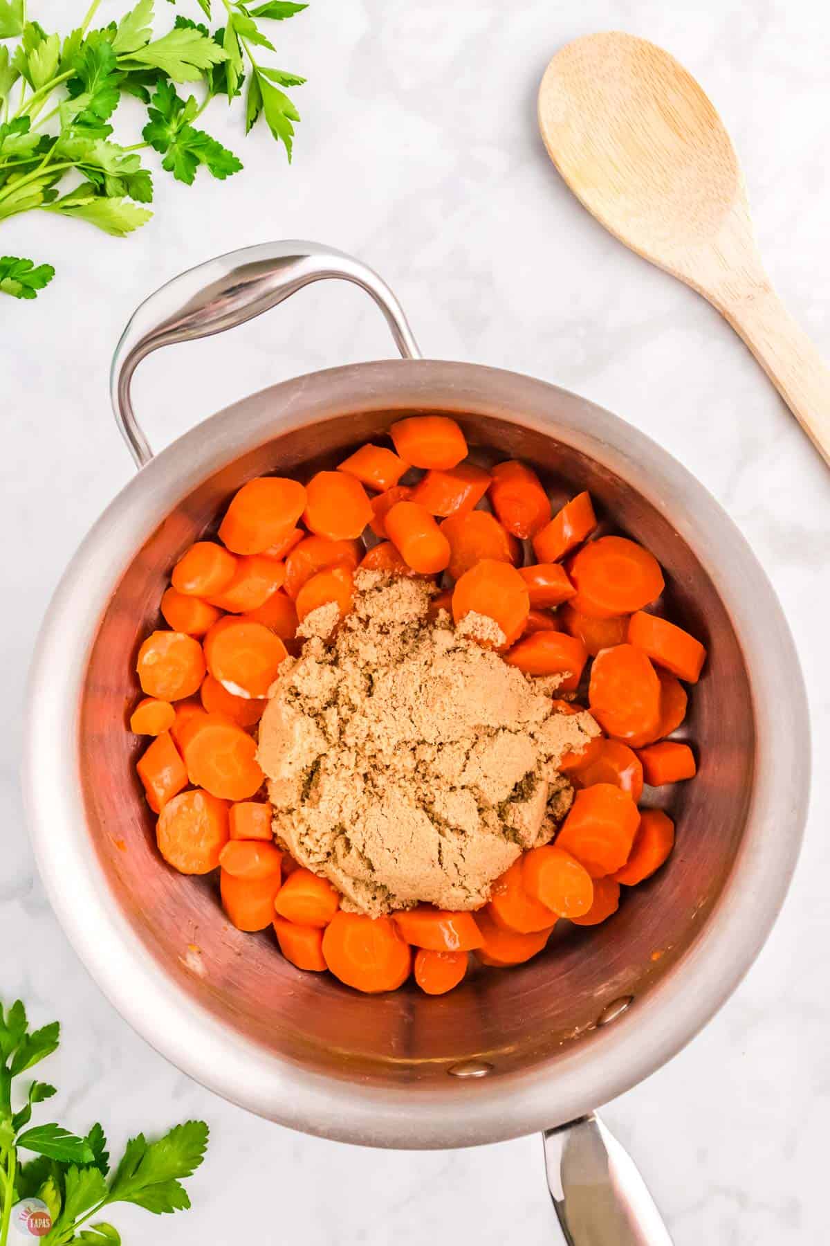 sliced carrots in a silver pot with brown sugar on top of them