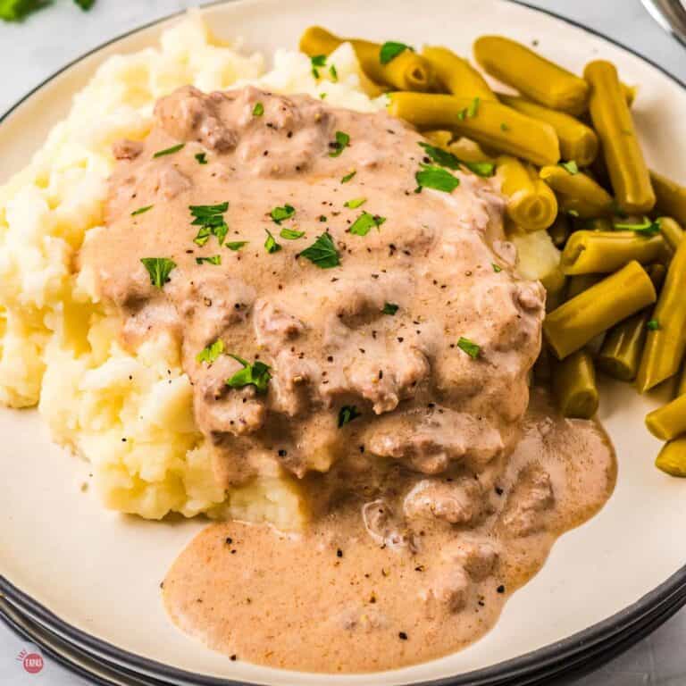 plate of mashed potatoes covered in hamburger gravy with a side of green beans