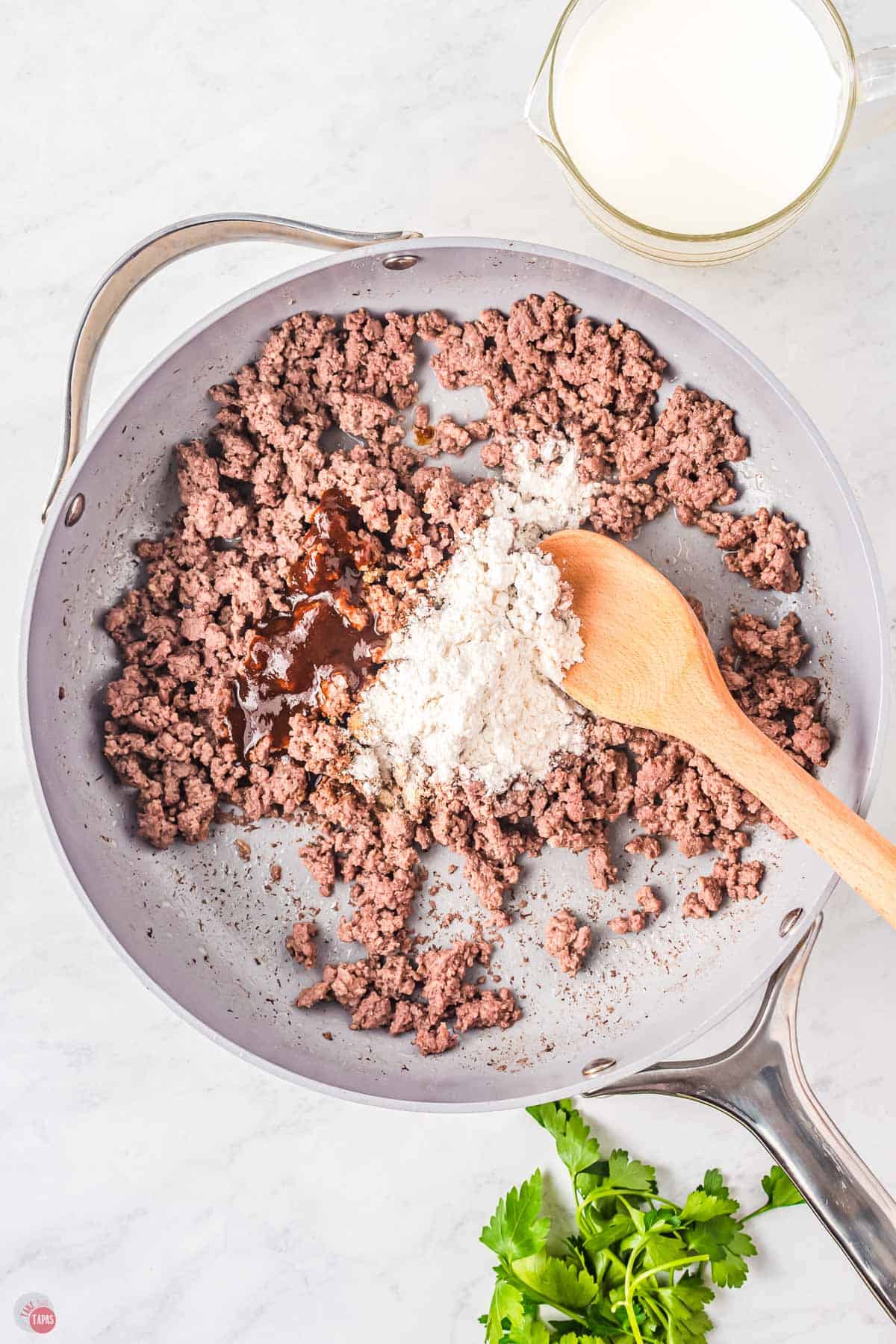 cooked ground beef in a skillet with flour sprinkled on top