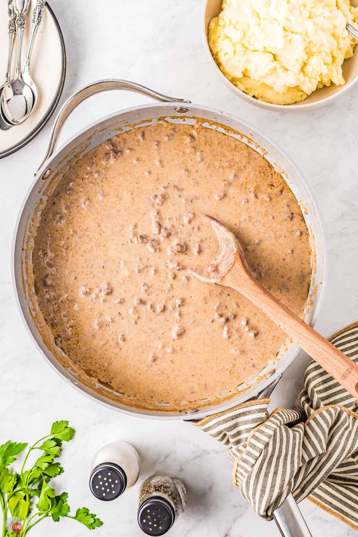 skillet with a wood spoon stirring gravy