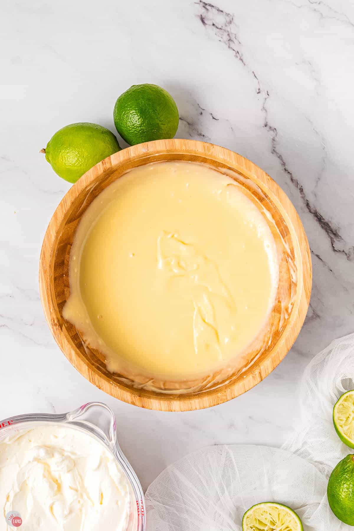lime dip in a wood bowl with limes next to it