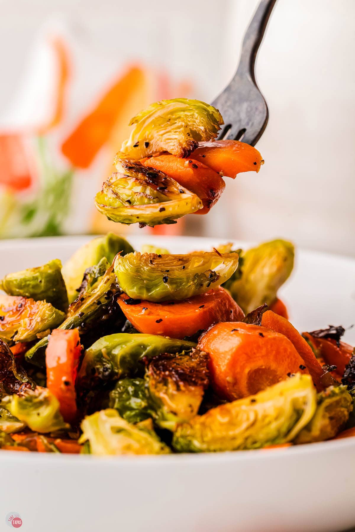 fork with a bite of sprouts and carrots over a plate