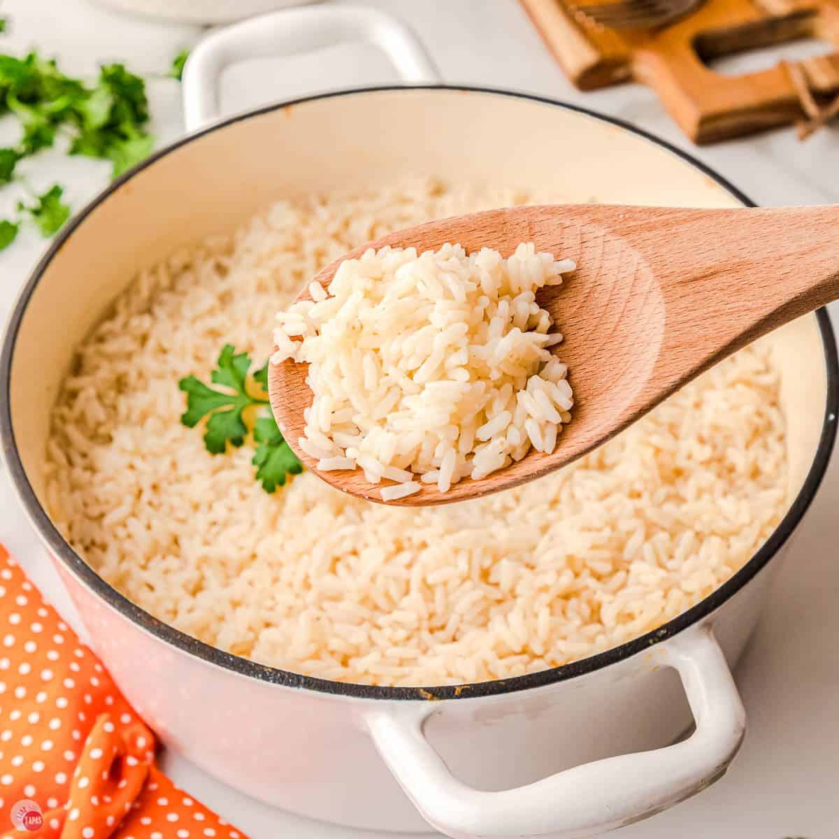 white pot filled with rice and wood spoon removing a scoop