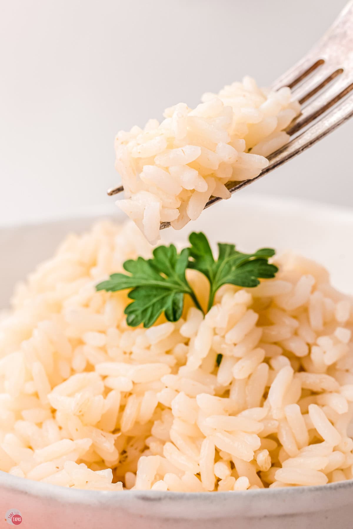 fork with bite of baked white rice over a bowl of rice