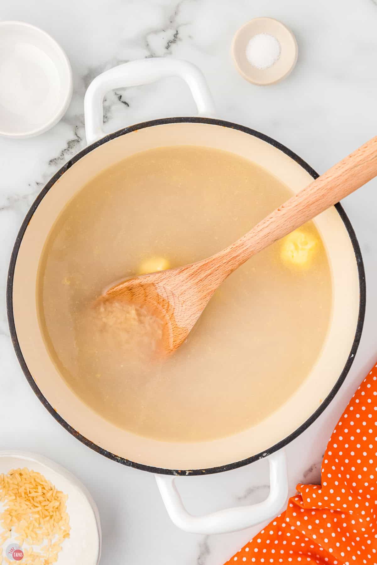 white pot with spoon stirring water in a pot with butter